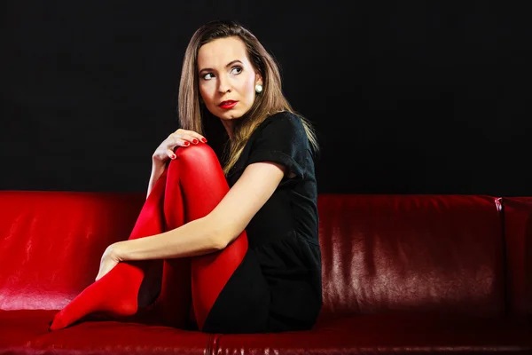 Sad woman sitting on red couch — Stock Photo, Image