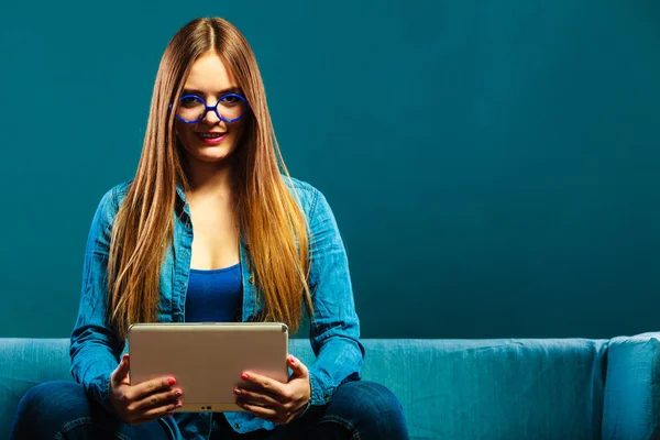 Žena s tabletem sedí na gauči modré barvy — Stock fotografie