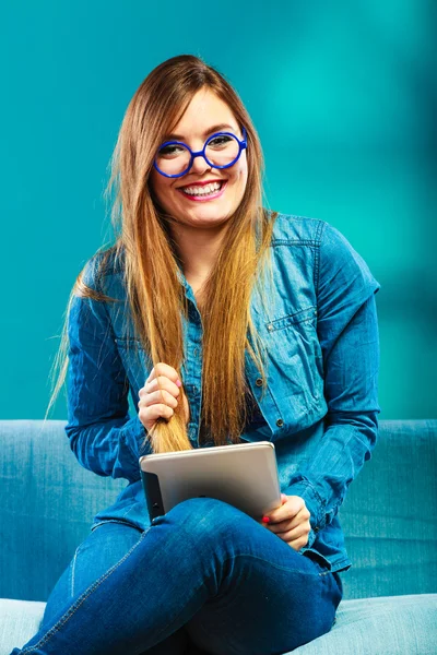 有平板电脑的女人坐在沙发上蓝色 — 图库照片