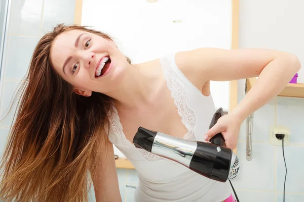 Женщина сушит волосы в ванной комнате — стоковое фото