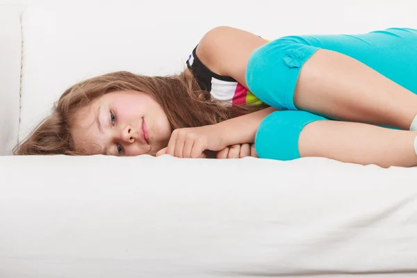 Уставшая ленивая маленькая девочка лежит на диване — стоковое фото