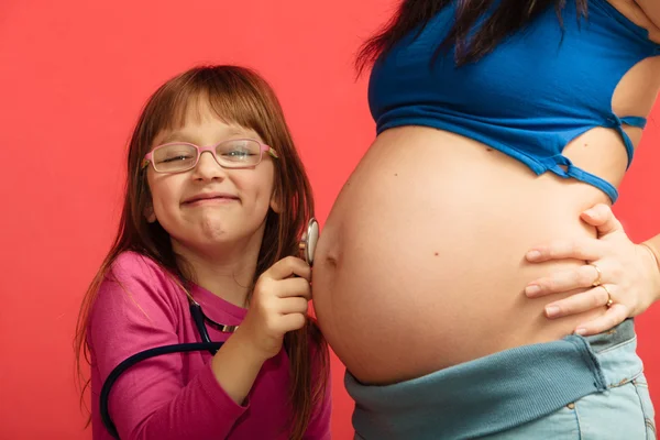 Liten flicka lyssnar på mammas mage — Stockfoto