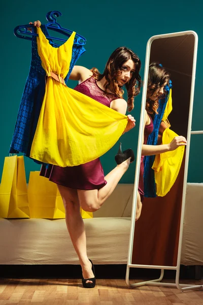 Женщина-покупатель держит вешалки с одеждой, смотрящей в зеркало — стоковое фото