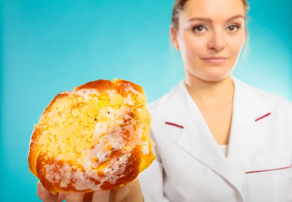 Woman dietician holding sweet bun — Stock Photo, Image