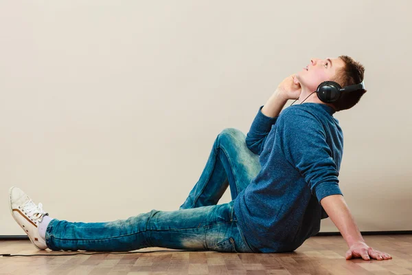 Homem com fones de ouvido sentado no sofá — Fotografia de Stock