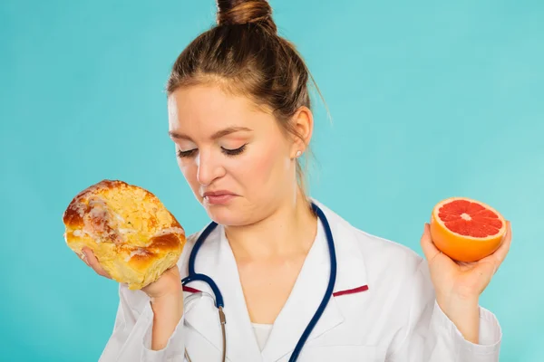 Dietista asqueroso con bollo dulce y pomelo . — Foto de Stock