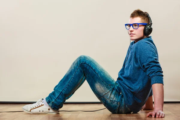 Joven con auriculares sentado en el suelo — Foto de Stock