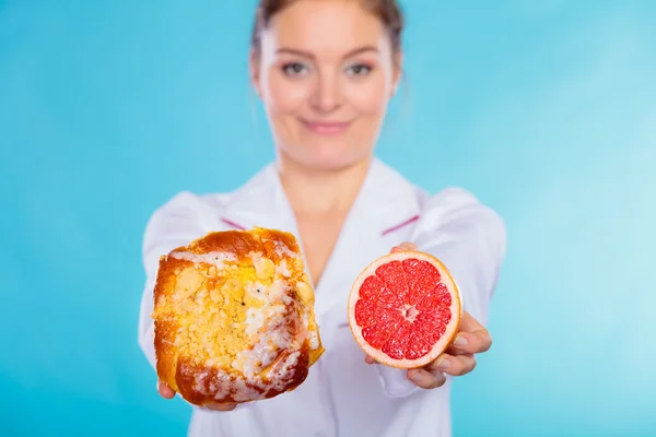 Nutritionist holding a cake and fruit — Stock Photo, Image