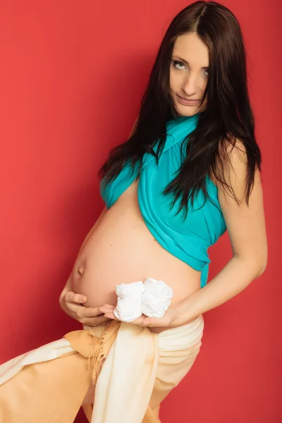 Femme enceinte avec de petites chaussures pour bébé à naître — Photo