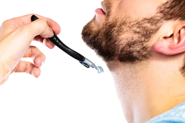 Молодой человек с бородой держит лезвие бритвы — стоковое фото