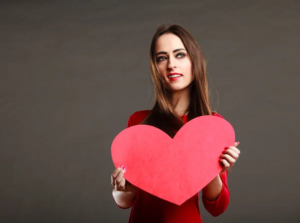 Vrouw in rode jurk houdt hart teken — Stockfoto