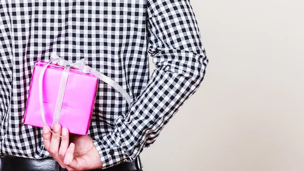 Un hombre escondiendo una caja de regalo atrás. Sorpresa de vacaciones . — Foto de Stock