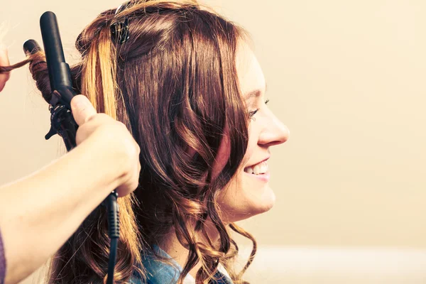 Estilista rizando el pelo para mujer joven. — Foto de Stock