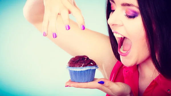 Mulher sorridente segura bolo de chocolate na mão — Fotografia de Stock