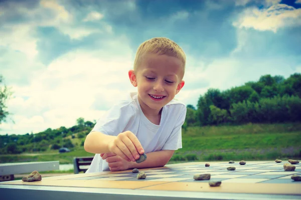 Petit garçon intelligent enfant jouer dames dans le parc — Photo