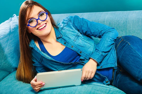 女人躺在沙发上蓝颜色上的平板电脑 — 图库照片