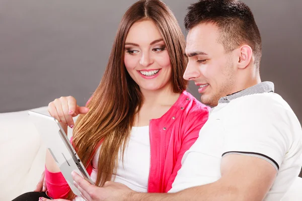 Couple with tablet sitting on couch at home — Stock Photo, Image
