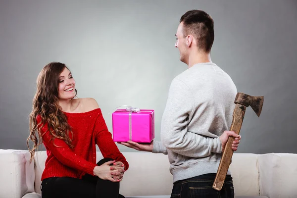 Insincire hombre sosteniendo hacha dando caja de regalo a la mujer — Foto de Stock