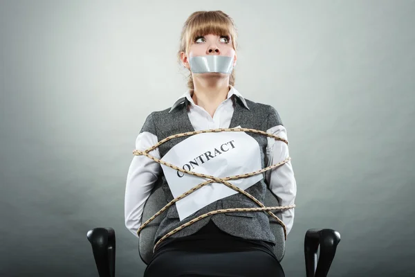 Businesswoman bound by contract with taped mouth.