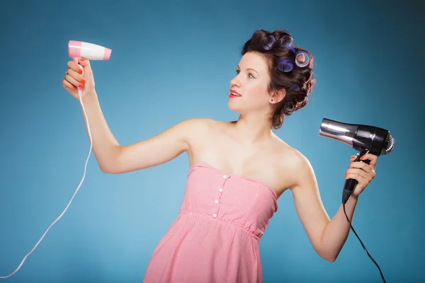 Girl with curlers in hair holds hairdreyers — Stock Photo, Image