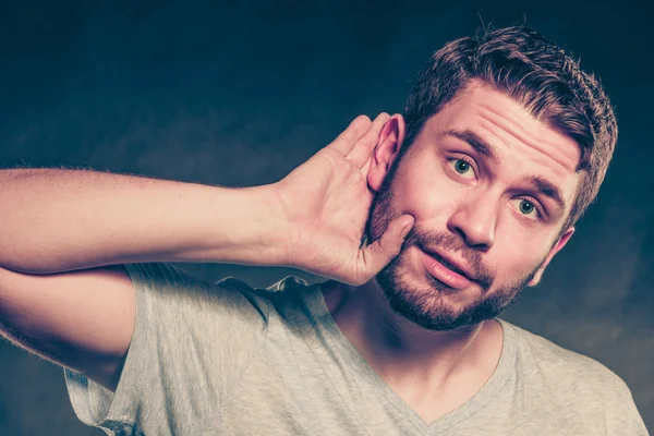Klepy muž odposlouchávání s rukou na uchu. — Stock fotografie