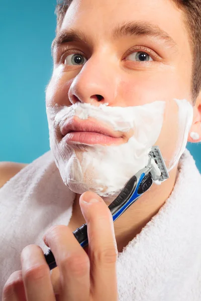 Молодой человек бреется бритвой с кремовой пеной . — стоковое фото