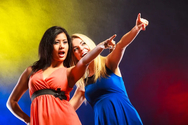 Two funny women showing something in dresses. — Stockfoto