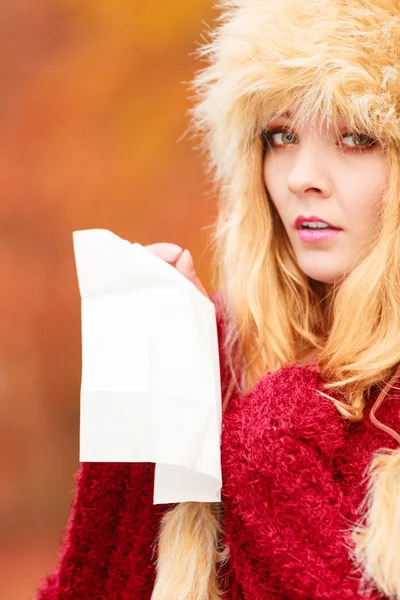 Sick woman in autumn park sneezing into tissue. — ストック写真