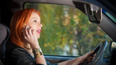girl talking on mobile phone while driving the car. clipart