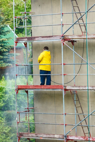 Hombre limpiando la pared. Andamios — Foto de Stock