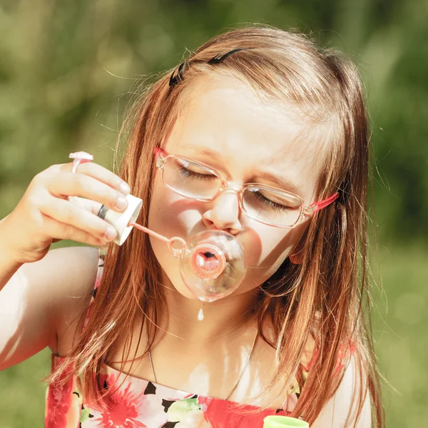 Bambina divertirsi soffiando bolle di sapone nel parco. — Foto Stock