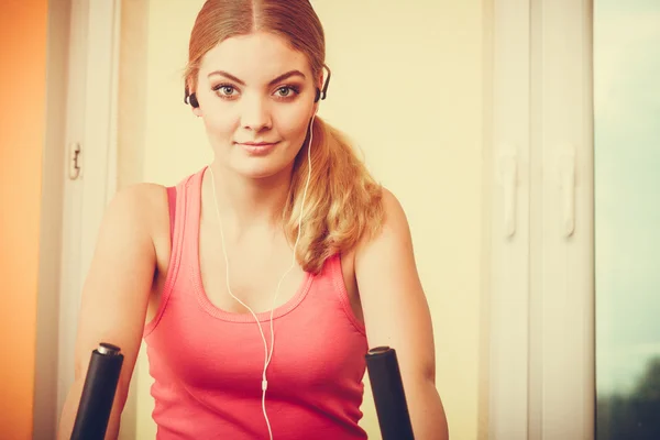 Woman on exercise bike listening music. Fitness — Stock Photo, Image