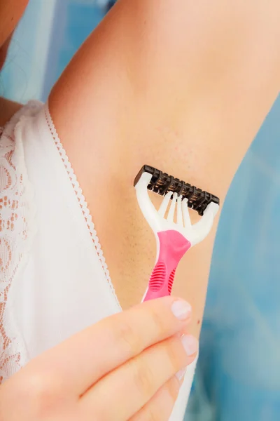 Женщина бреет подмышки бритвой в ванной комнате — стоковое фото