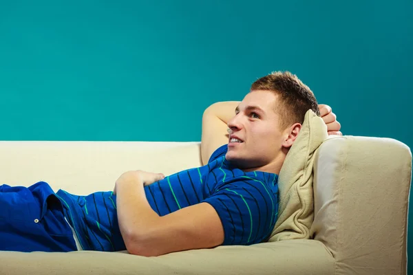 Young man relaxing on couch on blue — Stock Photo, Image