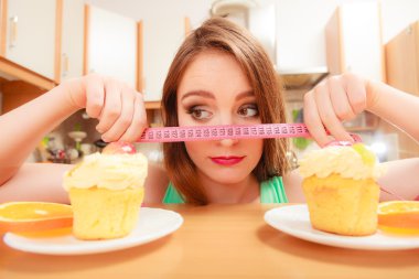 Woman with tape measure and cake. Diet dilemma. clipart