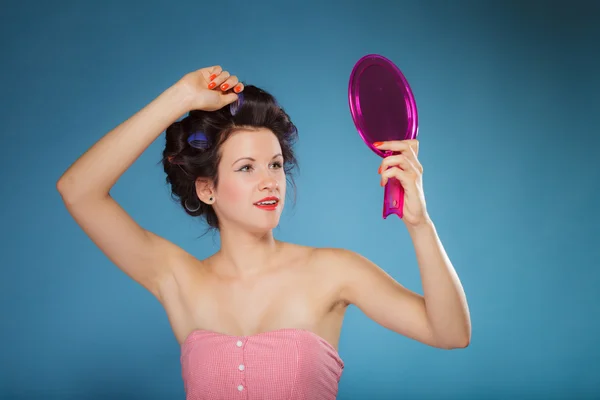 Ragazza styling capelli con bigodini guardando nello specchio — Foto Stock