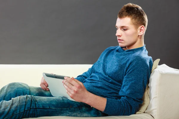 Junger Mann mit Tablet sitzt zu Hause auf Couch — Stockfoto