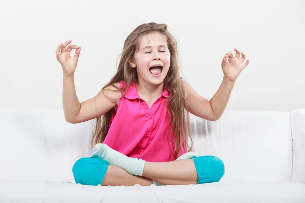 Смішна щаслива маленька дівчинка сидить на дивані роздумуючи — стокове фото