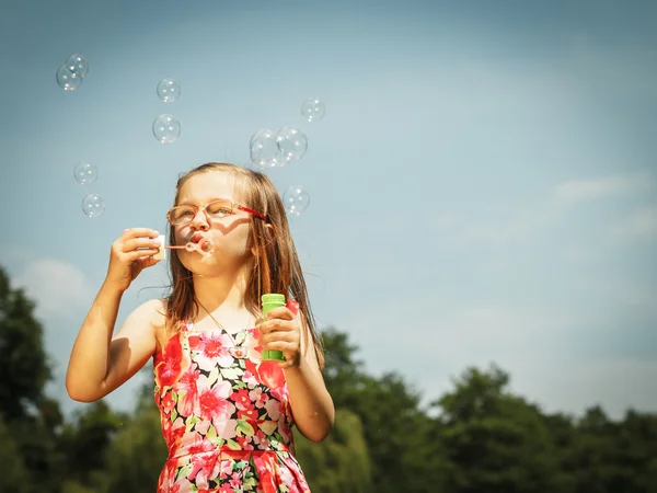 Little girl having fun blowing soap bubbles in park. — Stock Photo, Image