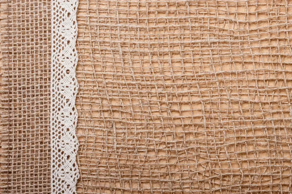 Lace ribbon on burlap cloth — Stock Photo, Image