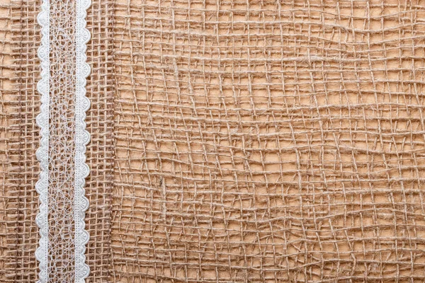 Lace ribbon on burlap cloth — Stock Photo, Image