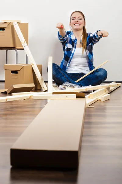 Woman moving into apartment assembly furniture. — Stock Image Woman moving into apartment assembly furniture. Stock Photo