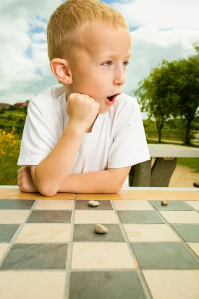 Child playing draughts or checkers board game outdoor — Stock Photo, Image