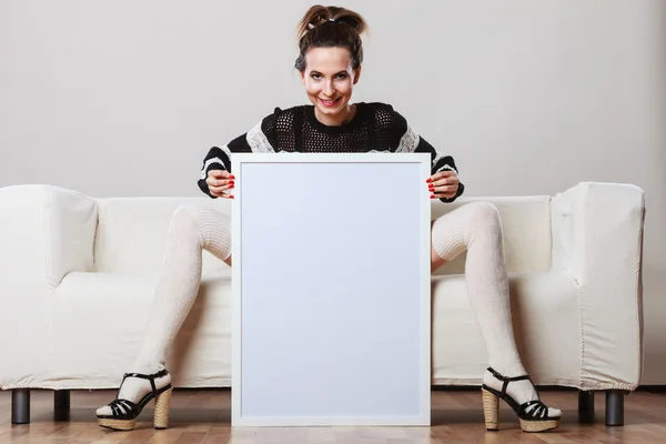 Woman on sofa holding blank presentation board. — Stock Photo, Image