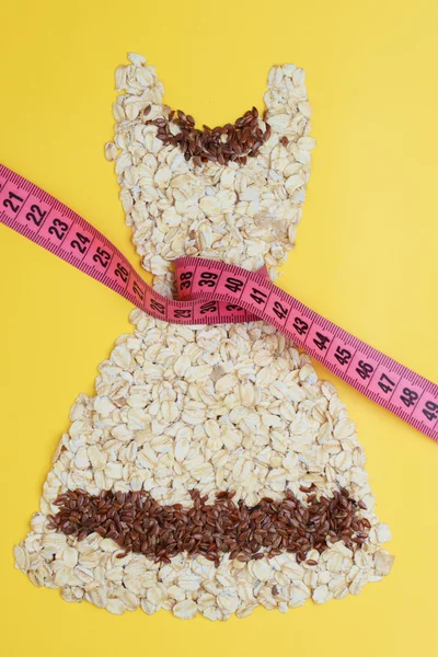 Dress shape made from oatmeal with measuring tape — Stock Photo, Image