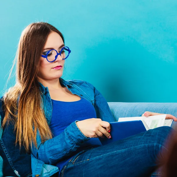 Woman sitting on couch reading book at home — Stock Photo, Image