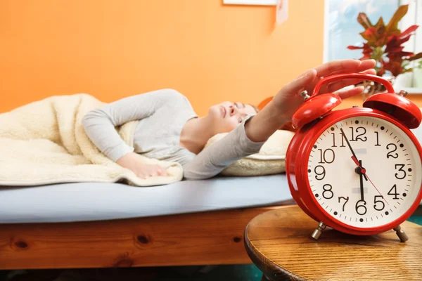 Woman waking up turning off alarm clock in morning — Stock Photo, Image