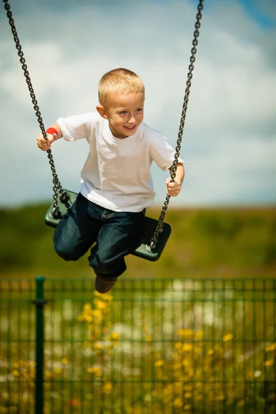 Маленький блондинка мальчик весело проводит время на качелях на открытом воздухе — стоковое фото