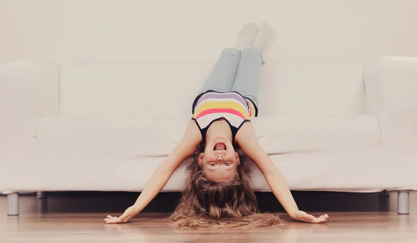 Ragazzina con i capelli lunghi a testa in giù sul divano — Foto Stock