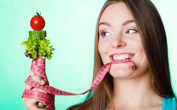 Mujer mordiendo cinta métrica con verduras . — Foto de Stock